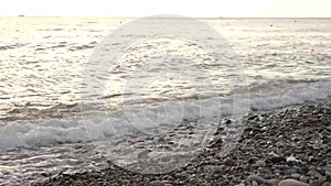 Seascape - water waves with foam surf on pebbles.