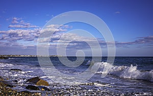 Seascape with white waves and clouds over the rocky windy beach