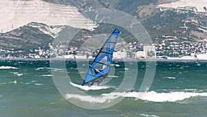 Seascape with windsurfing. a windsurfer rides on the waves catching the wind with a sail. the sea, mountains, waves.