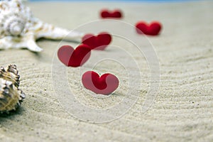 Seashells on the sand with red hearts, selective focus on the heart