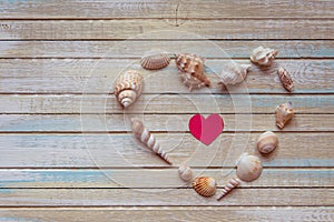 Seashells shaped heart on a wooden background top view