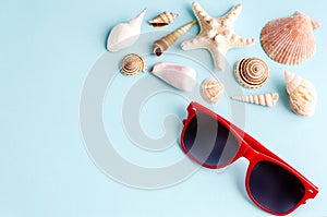 Seashells and sunglasses on a blue background with space for text