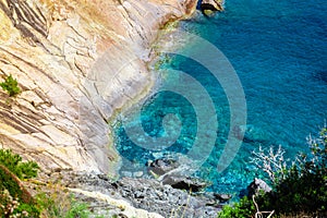 Seashore coastline with cliff and rocks on a mountain slope. Blue sea of the Island of Elba in Italy in the Tuscany region.