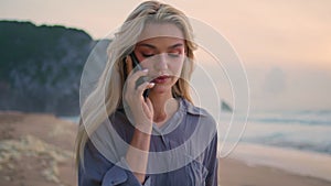 Seashore girl talking mobile phone in evening closeup. Beautiful sunset at sea