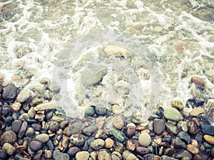 Seashore with pebbles and foam