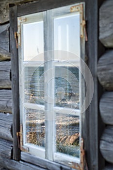 Seashore reflection in rustic cottage window of old wooden piscatorial house