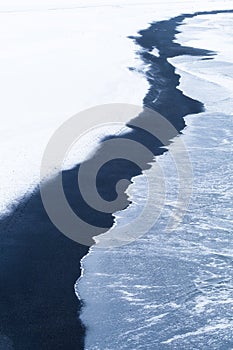 Seashore. View of stormy sea, black volcanic sand and snow. Landscape in Iceland. Winter view.