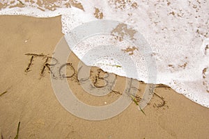 Seashore with the word Troubles on which a wave runs