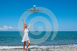 Seaside Escapade: Girl in White Dress on Stones, Plane Embracing the Blue Sea