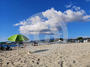 Seaside landscape with clouds and green umbrella