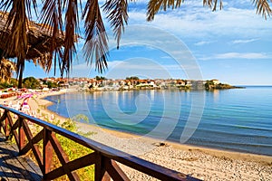 Seaside landscape - view from the cafe to the sandy beach with umbrellas and sun loungers