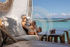 Seaside Leisure A young woman relaxes on a beachfront lounge chair, soaking up the sun with a view of the clear blue ocean and