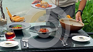 At a seaside restaurant, a waiter serves a table overlooking the ocean
