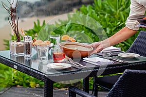 At a seaside restaurant, a waiter serves a table overlooking the ocean
