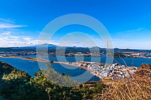 Seaside small city within seongsun ilchubong jeju island south korea with yellowish grass foreground