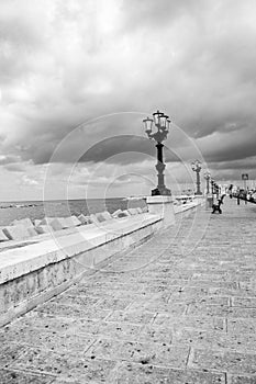 Seaside with street lamps in perspective black and white. Adriatic seascape monochrome. Italian coastline.
