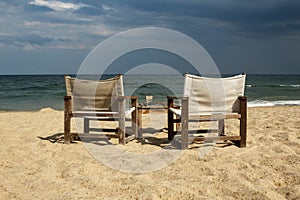 Seaside view with two chairs and table with an empty glass on it