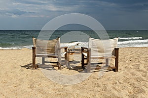 Seaside view with two empty chairs and table