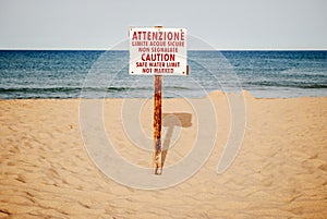Seaside warning sign at the beach in the early summer morning.
