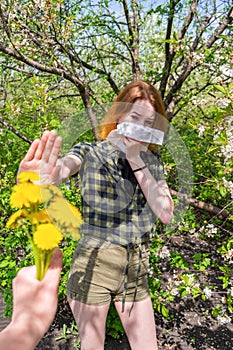 Season allergy to flowering plants pollen. Young woman with paper handkerchief covering her nose in garden and doing