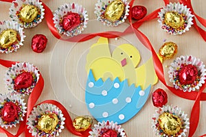 Season decoration: easter chocolate eggs frame with hand made hatched chicken in eggshell on wood background