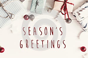 Season`s greetings text on modern christmas flat lay with orname