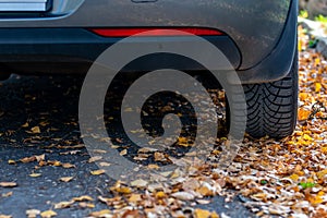 Season tire change. Car with new winter tires on the road for autumn leaves. Safety on a slippery autumn road.