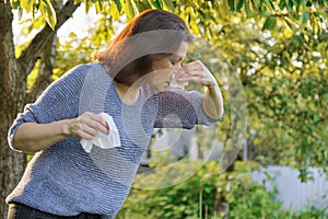 Seasonal allergies, woman with nasal wipe, sneezing, wiping nose outdoor