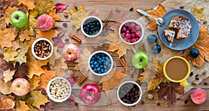 Seasonal autumn background. Frame of maple leaves and a cake, berries, raisins, apples, fruits, coffee and nuts over