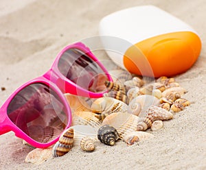 Seasonal concept, heap of shells, sunglasses and sun lotion