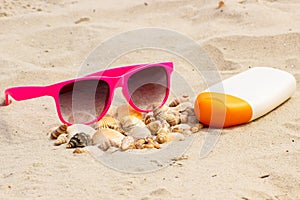 Seasonal concept, heap of shells, sunglasses and sun lotion