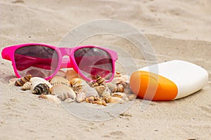 Seasonal concept, heap of shells, sunglasses and sun lotion