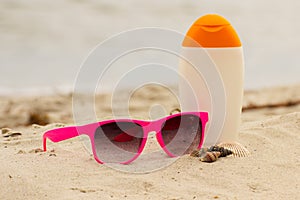 Seasonal concept, shells, pink sunglasses and sun lotion