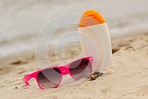Seasonal concept, shells, pink sunglasses and sun lotion