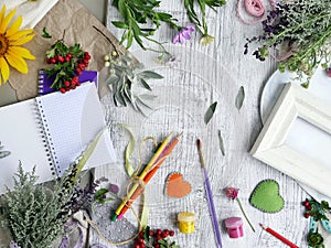 Seasonal decorative composition of flowers, berries, art and clerical materials, hearts made of felt on a background of light wood