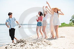 Seasonal feast at beach resort. Group of friends celebrating, resting, having fun on the beach in sunny summer day