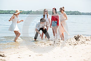 Seasonal feast at beach resort. Group of friends celebrating, resting, having fun on the beach in sunny summer day