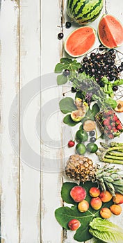 Seasonal fruit, vegetables and greens over wooden background, vertical composition