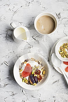 Seasonal healthy breakfast: yoghurt, chocolate granola, pink grapefruit, grapes, pistachios. Top view. Copy space. flat