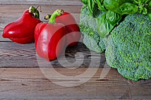 Seasonal raw ripe vegetables green broccoli, red bell pepper and fresh green basil on wooden background, healthy food concept, veg