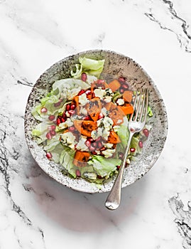 Seasonal salad with pumpkin, gorgonzola, pomegranate, iceberg on a light background, top view