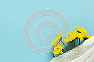 Seasonal spring summer allergy flowers concept. Yellow flowers with medical protective mask on blue background. Creative flat lay