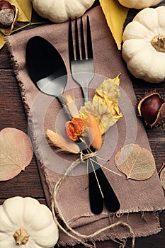 Seasonal table setting. Cutlery with pumpkins and autumn leaves on wood, flat lay