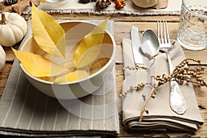 Seasonal table setting with fallen leaves and other autumn decor on wooden background