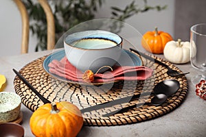 Seasonal table setting with pumpkins and other autumn decor in dining room