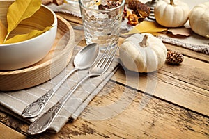 Seasonal table setting with pumpkins and other autumn decor on wooden background, closeup. Space for text