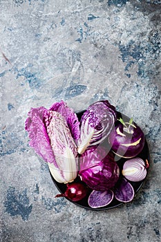 Seasonal winter autumn purple vegetables over gray stone table. Plant based vegan or vegetarian cooking concept. Clean eating food