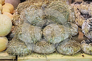 Seasoned cheese covered with straw after aging in a cave