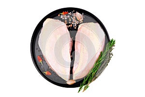 Seasoned chicken breast pieces with skin on a black plate, isolated on white, top view