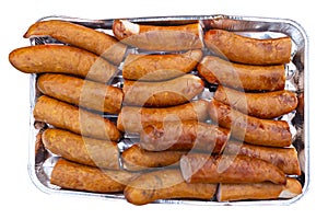 The seasoned and incised sausage lying on an aluminum tray, isolated on a white background with a clipping path.